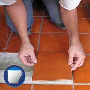 a tile worker laying ceramic floor tile - with Arkansas icon