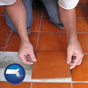 a tile worker laying ceramic floor tile - with Massachusetts icon