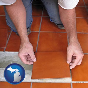 a tile worker laying ceramic floor tile - with Michigan icon