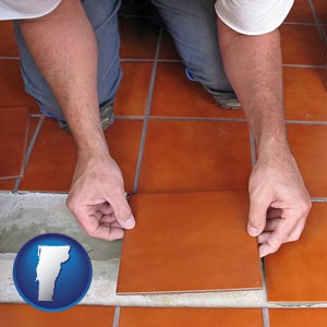 a tile worker laying ceramic floor tile - with Vermont icon
