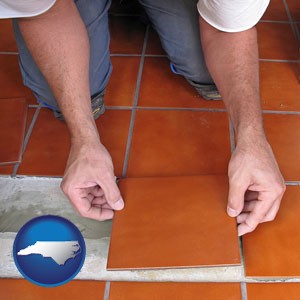 a tile worker laying ceramic floor tile - with North Carolina icon